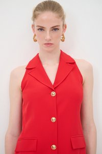 Blazer senza maniche rosso con colletto, caratterizzato da un'apertura frontale con bottoni e due tasche orizzontali. Bottoni dorati aggiungono un accento di contrasto.