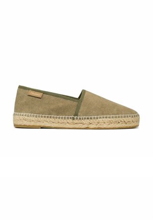 Olijfgroene instapper espadrille met een canvas bovenkant, gevlochten jute zool en een klein tan merklabel aan de zijkant tegen een witte achtergrond.