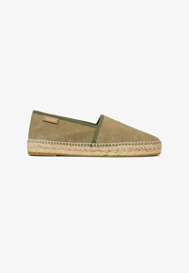 Olijfgroene instapper espadrille met een canvas bovenkant, gevlochten jute zool en een klein tan merklabel aan de zijkant tegen een witte achtergrond.
