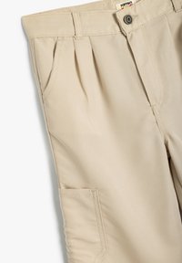 Beige bomuldsbukser med plisseringer, sidelommer og knaplukning. Glat tekstur med et klassisk fit design.