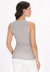 Top senza maniche con strisce verticali bianche e nere, design aderente e colletto rotondo. Il tessuto appare liscio con una leggera elasticità.