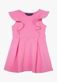 Rosa bomullsmodell med volangdetaljer på axlarna, ärmlös design och en utsvängd kjol; har en mjuk textur och midjesöm.