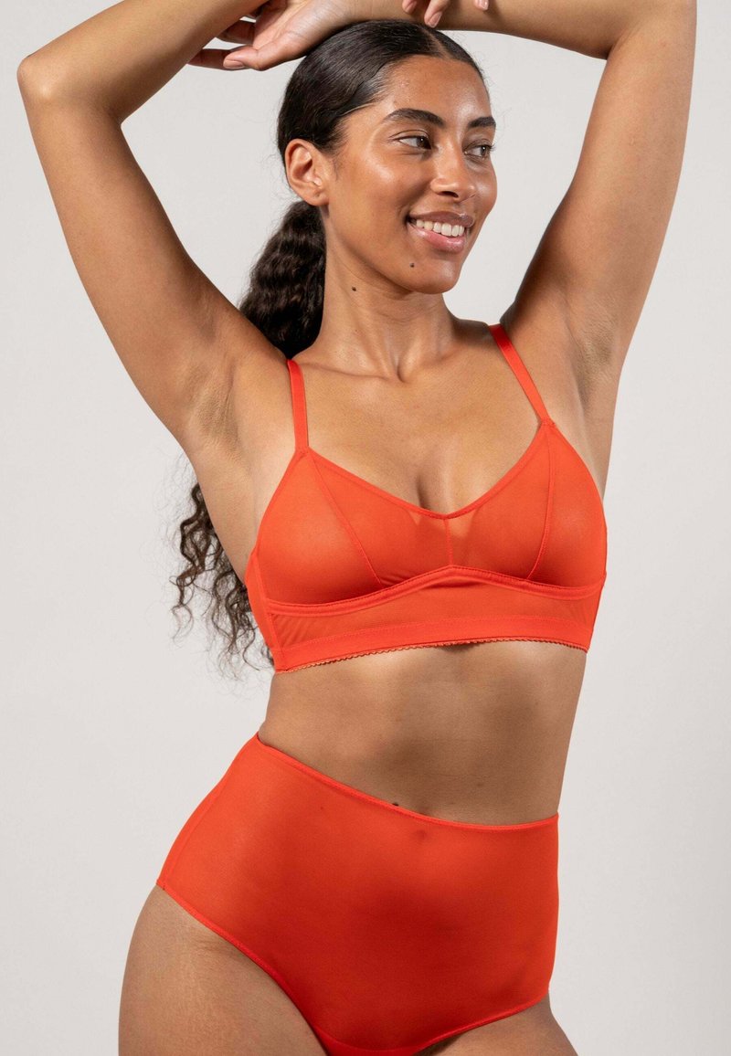 Röd bralette och högmidjade trosor, gjorda av ett mjukt tyg. Braletten har tunna band och en vågig nederkant. Minimalistisk design.