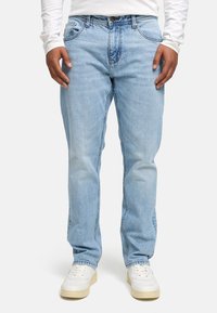 Jeans de mezclilla azul claro con un corte relajado, que cuentan con un diseño clásico de cinco bolsillos y un ligero desvanecimiento. Combinados con zapatillas blancas.