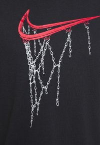 Svart T-shirt med en röd Nike-swoosh-design som liknar en basketkorg, med vita kedjedetaljer som faller neråt.