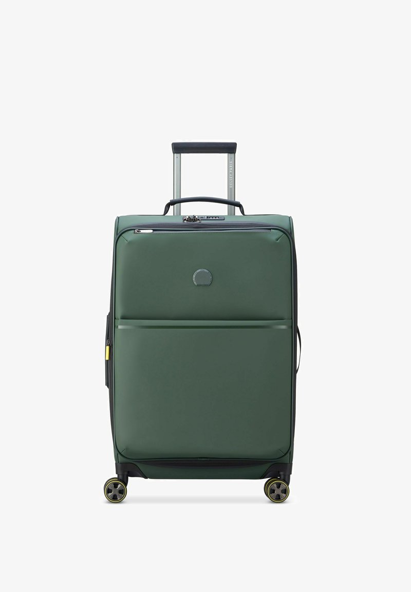 Valise souple verte avec une poignée télescopique, une poche à fermeture éclair à l'avant, quatre roues pivotantes et un logo circulaire sur le panneau avant.