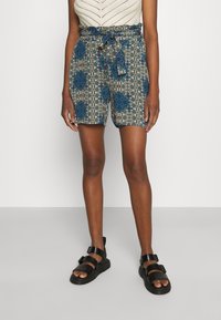 Pantalones cortos con estampado y cintura anudada, con un diseño floral azul sobre un fondo verde y beige; confeccionados con tela ligera.