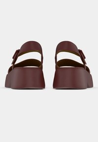 Πλατφόρμες σανδάλια σε μπορντό χρώμα με λείο τελείωμα και ανοιχτή φτέρνα. Διαθέτουν ρυθμιζόμενο λουράκι και πλατιά κυρτά πέλματα για σταθερότητα.