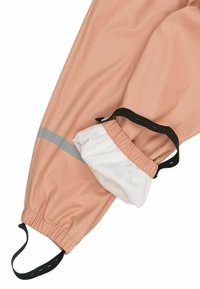Pantalon imperméable couleur pêche avec une bande grise réfléchissante, des poignets élastiques et une doublure intérieure blanche. Sangle noire réglable pour l'ajustement.