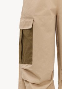 Pantalon beige avec grande poche cargo vert olive avec rabat sur le côté de la jambe.