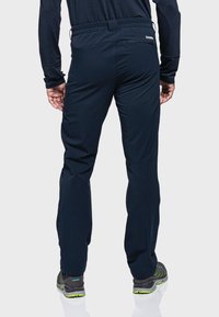 Granatowe spodnie outdoorowe z elastycznym pasem, bocznymi kieszeniami i eleganckim wzornictwem. Materiał wydaje się być trwały z gładką fakturą, odpowiedni do aktywnego użytkowania.