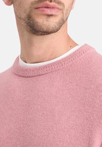 Suéter rosa hecho de un suave material de punto con un escote redondo y un sutil detalle texturizado en el cuello.
