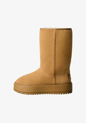 Brune ruskind ankelstøvle med rund tå, blød pelsforing øverst og flad gummisål med mønster for bedre greb.