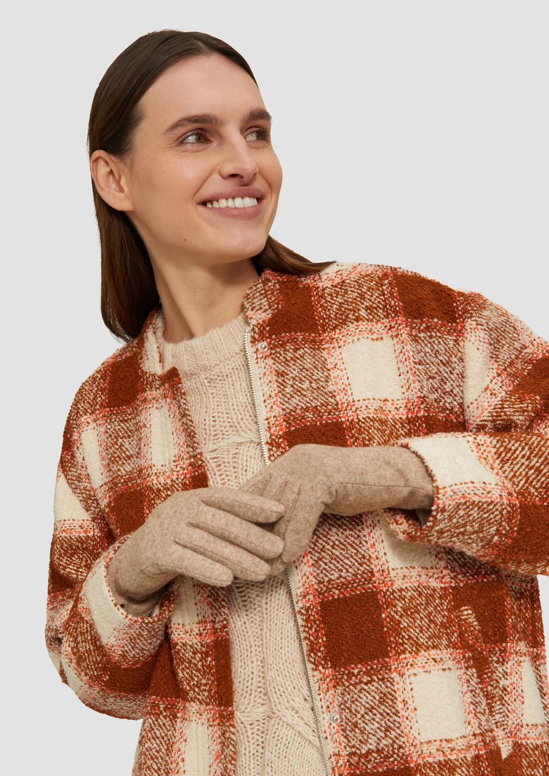 Gecontroleerde wollen mantel in rood en crème, met daaronder een gebreid trui van textuur en beige handschoenen. Heeft een relaxte pasvorm en een ritssluiting.