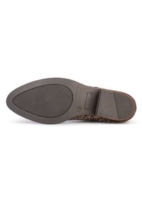 Semelle de chaussure en imprimé léopard avec une base en caoutchouc noir lisse, dotée d'un motif de grip texturé et d'un talon légèrement surélevé pour la stabilité.