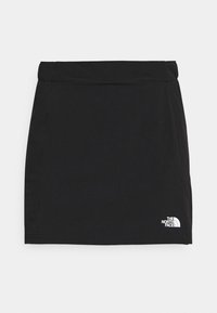 Falda negra con una textura suave, cintura elástica y un pequeño logo blanco en la parte inferior derecha. Diseño sencillo, corte recto, por encima de la rodilla.