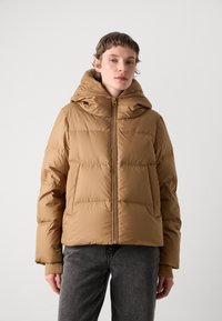 Doudoune marron avec capuche, dotée de coutures horizontales, d'un zip à l'avant et de poches latérales. Les poignets possèdent des accents en tricot côtelé.