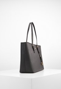 Sort læder tote taske med dobbelte håndtag, rektangulær form, gyldne hardware-detaljer og en lynlåslukning. Glat tekstur med syede detaljer.