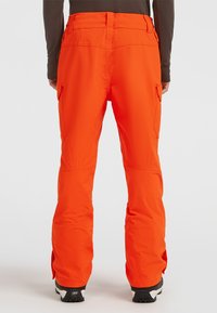 Oranje skibroek met een comfortabele pasvorm, voorzien van zijcargo pockets en versterkte onderbenen. Gemaakt van duurzaam, waterafstotend materiaal.