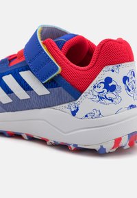 Blue athletic shoes feature a red mesh collar and adjustable strap. The heel displays a white and blue Mickey Mouse pattern. Rubber sole accents.