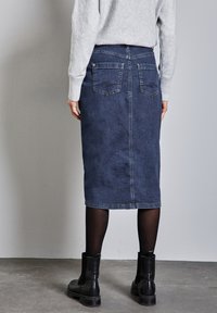 Mörkblå denim midi kjol med rak skärning, bakfickor och en fåll precis under knät. Matchad med svarta ankelboots.