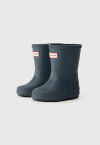 Bottes de pluie en caoutchouc bleu marine avec une semelle texturée, un orteil arrondi et un bord décoratif. Présente une étiquette Hunter blanche et rouge à l'avant.
