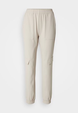 Beige joggebukser med elastisk midjebånd, to sidelommer og innsnevret benåpning. Laget av myk, lett stoff.