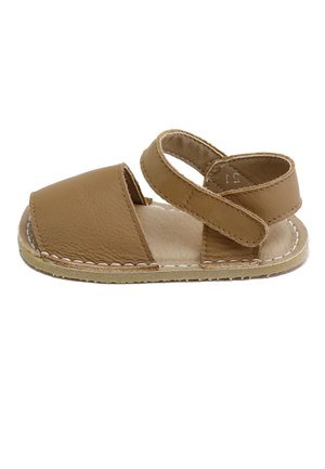 Sandalia marrón para niño pequeño con puntera cerrada, correa ajustable en el tobillo, suela blanda y detalle de costura blanca en el borde de la suela.