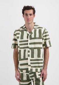 Korte mouwen knoopshirt in beige met groene abstracte patronen. Gemaakt van textuurstof, heeft een relaxte pasvorm en een kraag.