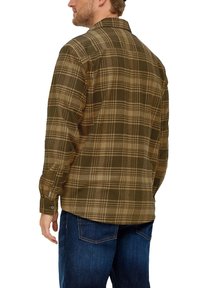Bruine en beige geruite flanellen shirt met lange mouwen, knoopmanchetten en een kraag, gecombineerd met donkerblauwe jeans.