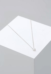 Sølvstjerne vedhæng halskæde med en fin kæde, der har en struktureret stjern charme og en lille perle. Glat finish, minimalistisk design.