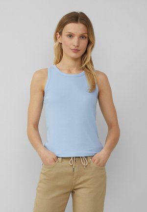 Lichtblauw geribbeld mouwloos topje met een ronde halslijn, gecombineerd met beige broek met een trekkoord in de taille en zilverkleurige hardware accenten.