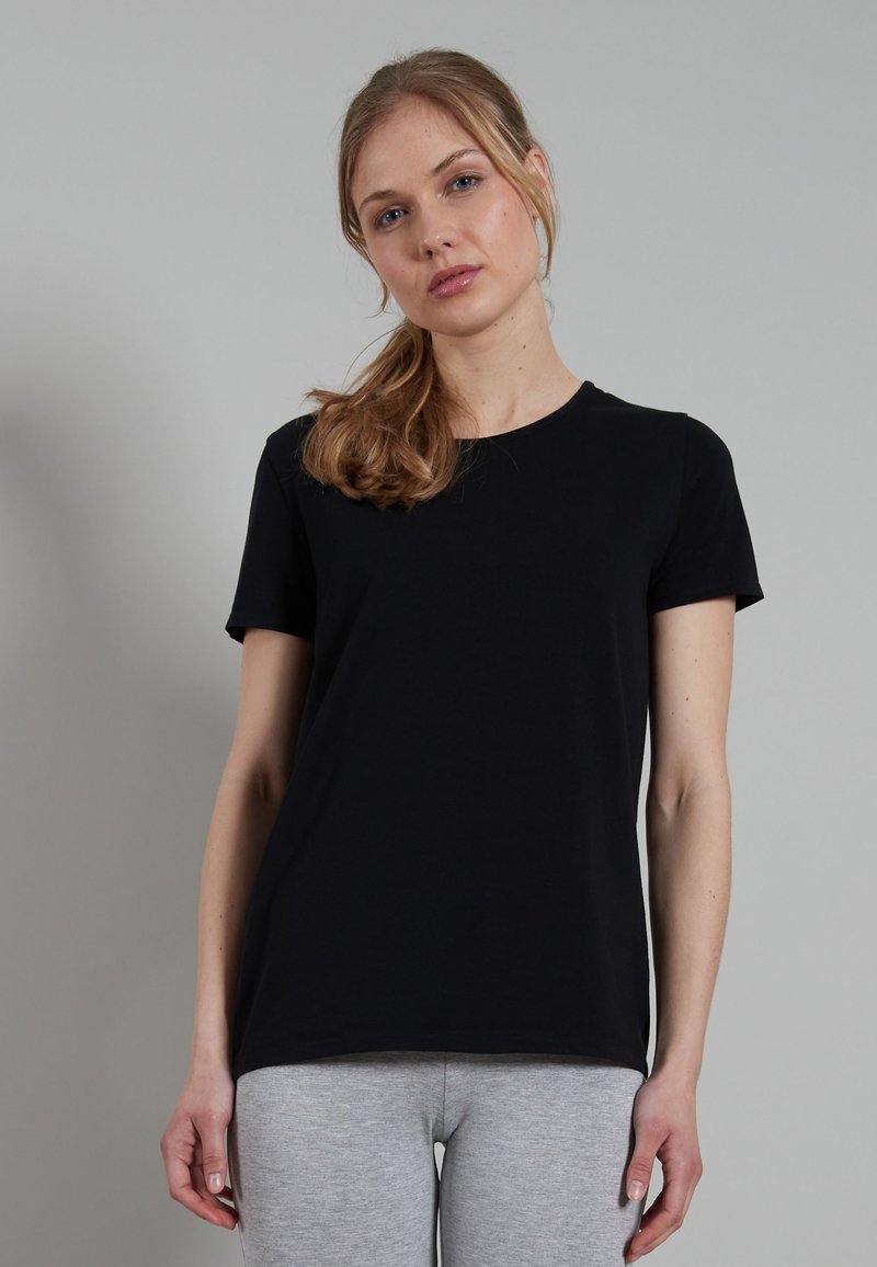 Black short-sleeve t-shirt in soft cotton material, featuring a round neckline and a relaxed fit. Paired with gray leggings.
