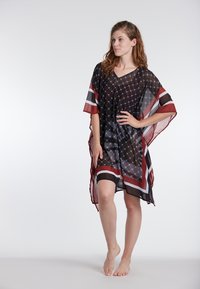 Proziran črn kaftan z geometrijskim vzorcem, rdečimi in belimi črtami, ohlapen kroj, V-izrez in tekoči rokavi. Lahka tkanina.