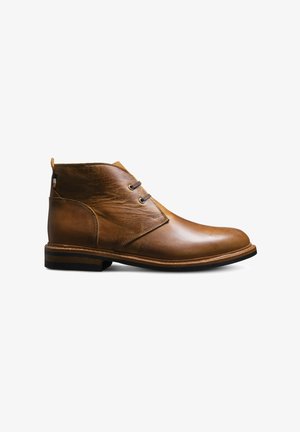 Brown leather ankle boot with two eyelets, rounded toe, pull tab at heel, layered sole, and black rubber outsole.