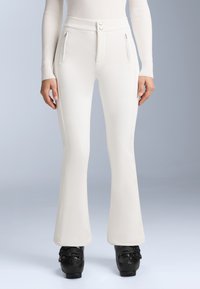 Pantaloni flared albi, confecționați dintr-un material neted, cu talie înaltă, două buzunare cu fermoar și două butoane în față. Încălțăminte neagră cu fâșii.