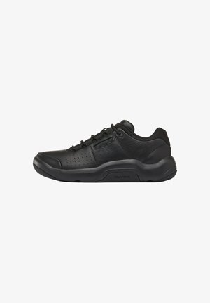 Zapatilla negra de corte bajo con cierre de cordones, parte superior de cuero perforado, cuello acolchado y suela gruesa de goma con la marca DMAX.