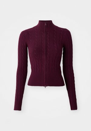 Mørk lilla kabelstrikket hettegenser med ribbestrikkede mansjetter, nederkant og ståkrage, vist flatt på en hvit bakgrunn.