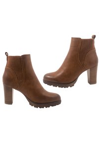 Botas de tobillo marrones con un acabado de piel suave, paneles laterales de malla y una suela de goma texturizada. Diseñadas con un tacón apilado de altura media.