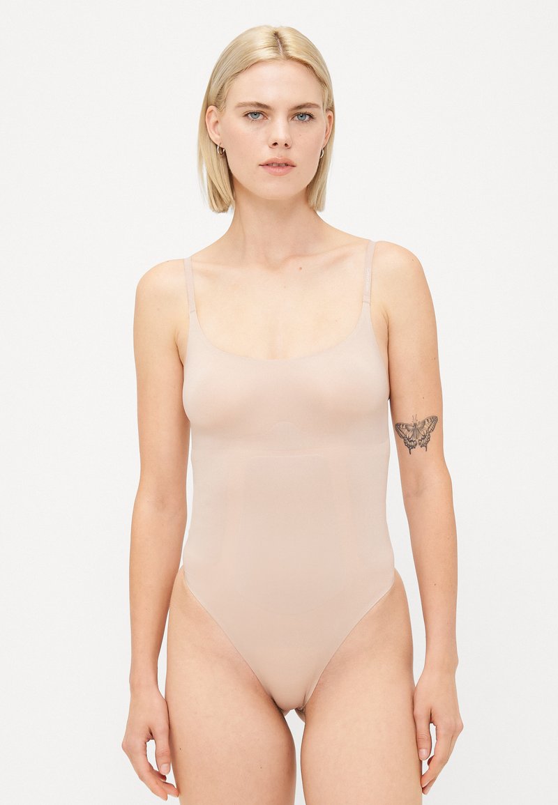 Body nude con tirantes ajustables, textura suave y corte tipo braga. Presenta un escote redondeado y un diseño sin costuras para una visibilidad mínima.