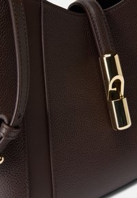 Bolsa de couro castanho com uma superfície texturizada, apresentando um fecho de tom dourado e uma alça suave que acentua o design.