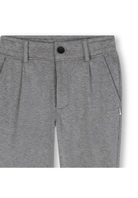 Sive hlače s puloverjem iz mehkega blaga, opremljene s sprednjim gumbom, gubami in stranskimi žepi. Gladek tekstura z nežnim vzorcem.