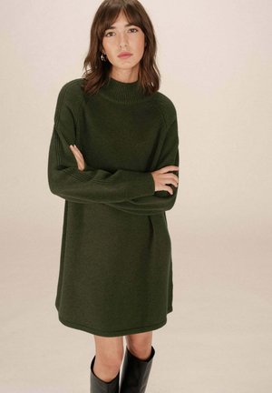 Robe-sweater tricotée vert foncé avec un col haut, des manches longues et une coupe décontractée, comportant des accents côtelés et un ourlet droit.