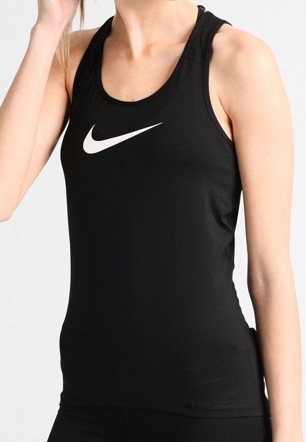 Femme portant un débardeur de sport noir ajusté avec un logo Nike Swoosh blanc sur la poitrine, sur un fond uni.
