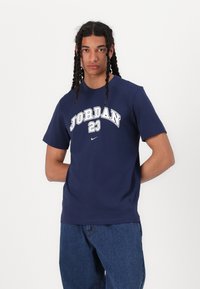Námorně modré bavlněné tričko s bílým potiskem "JORDAN 23" a logem Nike. Krátké rukávy, kulatý výstřih, standardní střih, hladká textura.