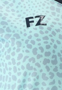 Ljusblått tyg med grå leopardfläckar och svarta stiliserade bokstäver "FZ" i mitten.