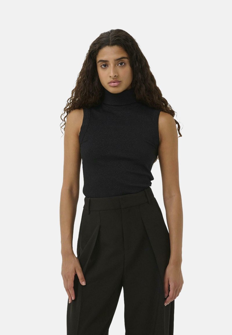 Schwarzes ärmelloses Rollkragensweatshirt in Rippstruktur, kombiniert mit hochtaillierten, maßgeschneiderten schwarzen Hosen mit Bundfalten. Einfaches, monochromatisches Design.