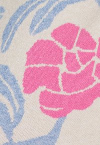 Gebreide stof met een roze bloemmotief en blauwe bladeren op een lichtbeige achtergrond. Getextureerd patroon met contrasterende kleuren.