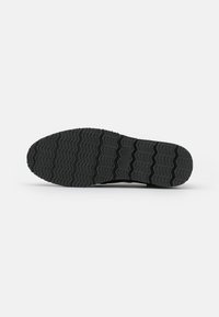 Soletta in gomma nera con un motivo a zigzag. Presenta punti rialzati per una migliore aderenza e una superficie liscia sul tallone. Materiale durevole e testurizzato.