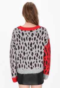 Maglione grigio con dettagli rossi, caratterizzato da un motivo a leopardo in nero e marrone. Tessuto morbido, taglio comodo e colletto a coste.